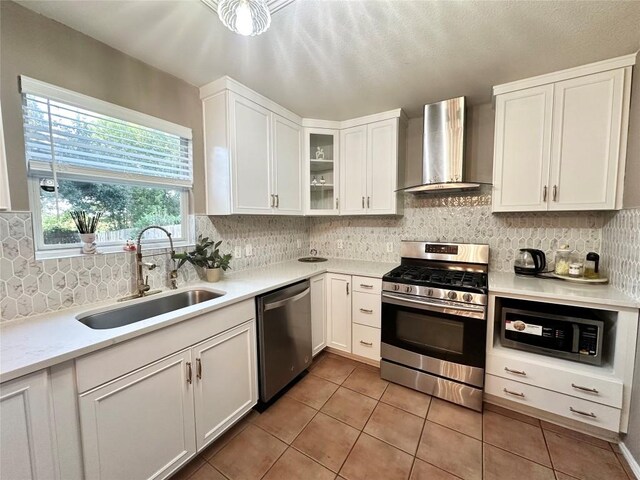 6116 Speyside Dr, Austin, TX 78754 - kitchen featuring appliances with stainless steel finishes, wall chimney exhaust hood, light tile patterned flooring, white cabinetry, and backsplash