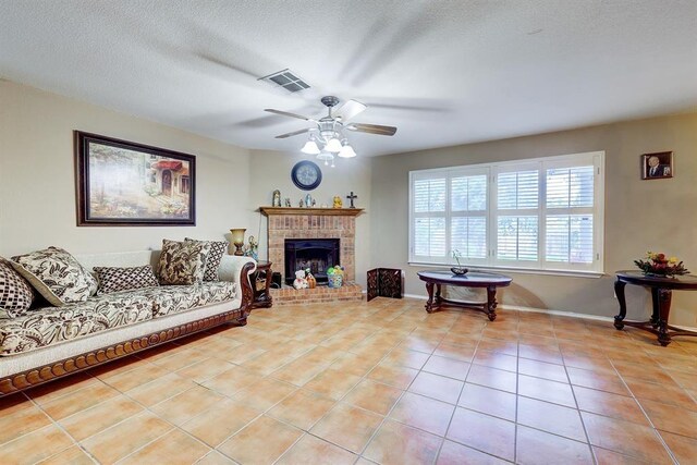 6116 Speyside Dr, Austin, TX 78754 - living area featuring light tile patterned flooring, ceiling fan, a brick fireplace, and a textured ceiling