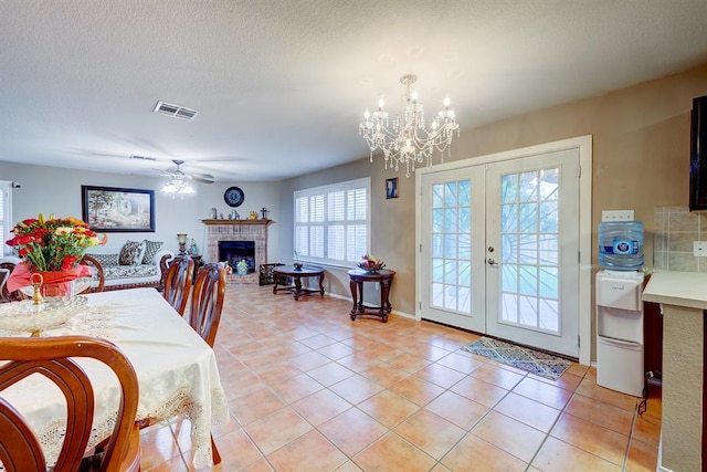 6116 Speyside Dr, Austin, TX 78754 - dining room with a brick fireplace, french doors, a chandelier, ceiling fan, and light tile patterned floors