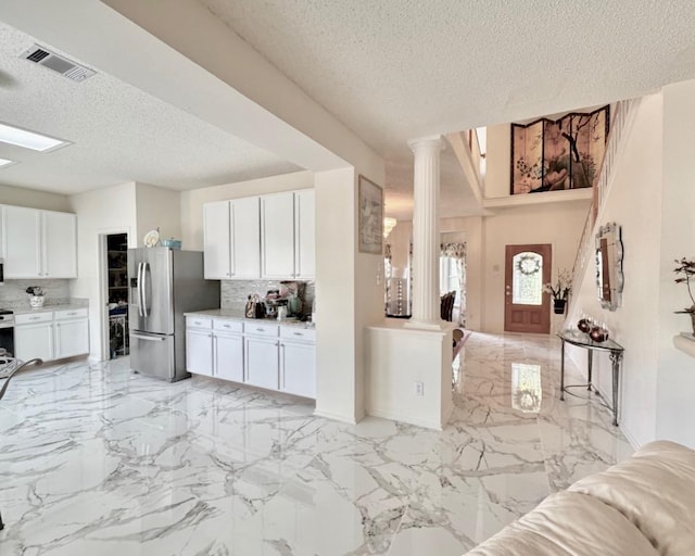 15304 Iola Cv, Austin, TX 78717 - kitchen featuring stainless steel fridge, a textured ceiling, decorative columns, backsplash, and white cabinetry