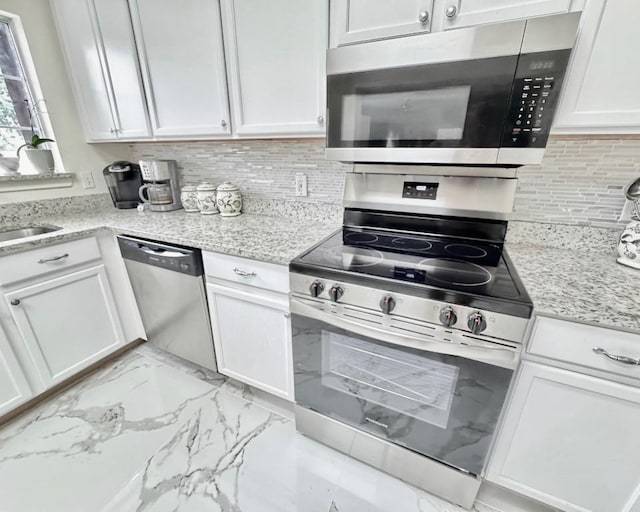 15304 Iola Cv, Austin, TX 78717 - kitchen with stainless steel appliances, white cabinets, light marble finish floors, backsplash, and light stone counters
