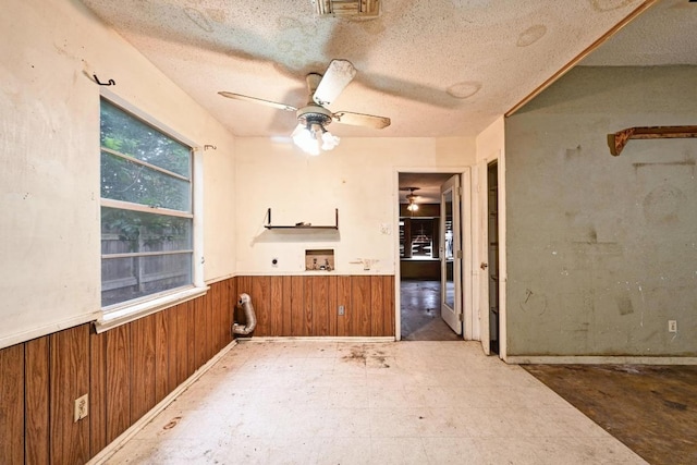10410 Margra Ln, Austin, TX 78748 - spare room with a wainscoted wall, a ceiling fan, wood walls, and a textured ceiling