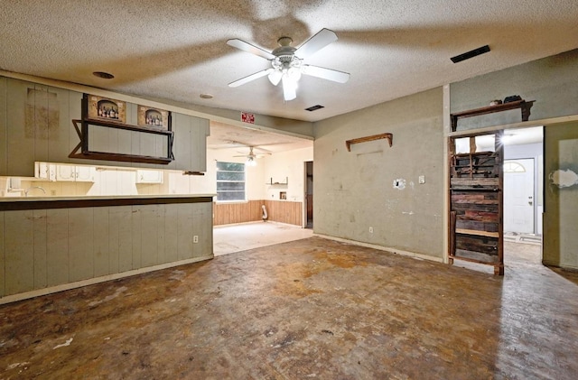 10410 Margra Ln, Austin, TX 78748 - unfurnished living room with ceiling fan, a textured ceiling, unfinished concrete floors, and wood walls