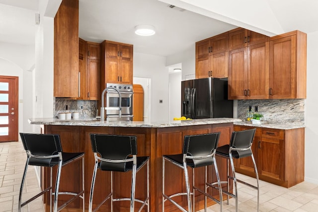 10808 Redmond Rd, Austin, TX 78739 - kitchen featuring fridge with ice dispenser, backsplash, a peninsula, and brown cabinetry