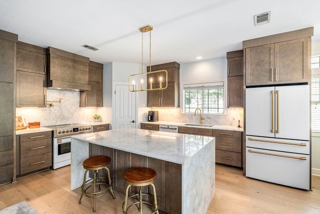 3 Stillmeadow Ct, The Hills, TX 78738 - kitchen featuring premium appliances, light wood-style flooring, dark brown cabinetry, a center island, and recessed lighting