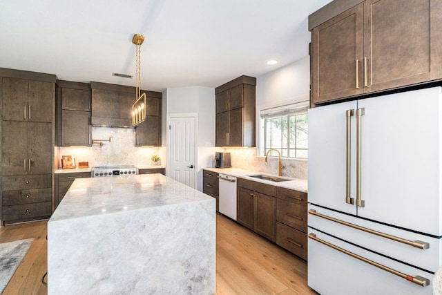 3 Stillmeadow Ct, The Hills, TX 78738 - kitchen with white appliances, light wood-style flooring, dark brown cabinets, a center island, and backsplash
