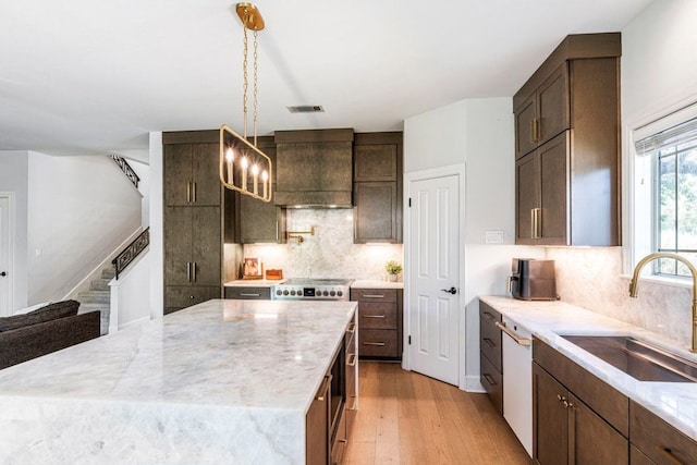 3 Stillmeadow Ct, The Hills, TX 78738 - kitchen with light wood-type flooring, dark brown cabinets, white dishwasher, and decorative backsplash