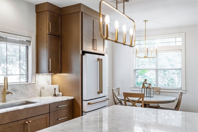 3 Stillmeadow Ct, The Hills, TX 78738 - kitchen featuring high end fridge, a chandelier, light stone counters, backsplash, and pendant lighting