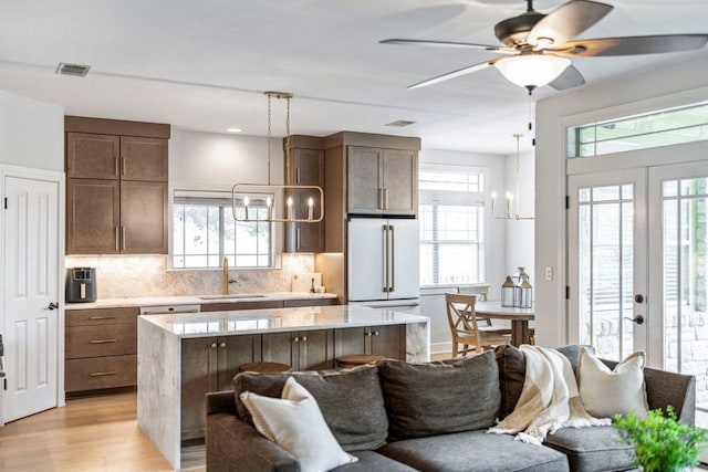 3 Stillmeadow Ct, The Hills, TX 78738 - kitchen with freestanding refrigerator, open floor plan, light countertops, decorative backsplash, and light wood-style flooring