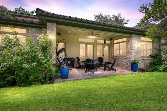 3 Stillmeadow Ct, The Hills, TX 78738 - back of house at dusk with stone siding, a ceiling fan, a patio, and a lawn