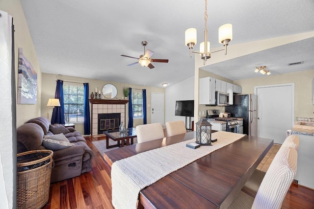 1111 Fairlawn Cv, Round Rock, TX 78664 - dining space with wood finished floors, vaulted ceiling, ceiling fan, a tiled fireplace, and a textured ceiling