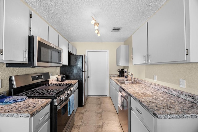 1111 Fairlawn Cv, Round Rock, TX 78664 - kitchen featuring appliances with stainless steel finishes, a textured ceiling, and rail lighting