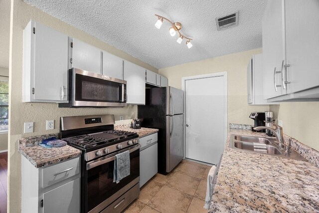 1111 Fairlawn Cv, Round Rock, TX 78664 - kitchen featuring appliances with stainless steel finishes, a textured ceiling, light countertops, and track lighting
