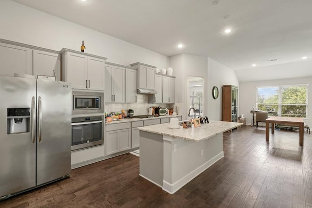 15617 Cinca Terra Dr, Bee Cave, TX 78738 - kitchen with stainless steel appliances, an island with sink, dark wood-style floors, light stone counters, and backsplash