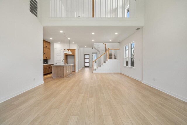 418 Darley Oak Dr, Dripping Springs, TX 78620 - unfurnished living room featuring a high ceiling, stairs, light wood finished floors, and recessed lighting