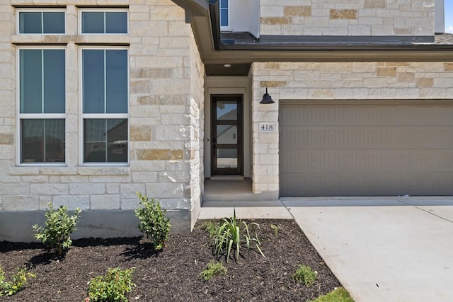 418 Darley Oak Dr, Dripping Springs, TX 78620 - view of exterior entry with stone siding, a garage, and concrete driveway
