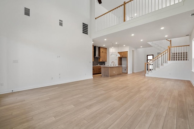 418 Darley Oak Dr, Dripping Springs, TX 78620 - unfurnished living room with a towering ceiling, light wood-type flooring, stairway, and recessed lighting