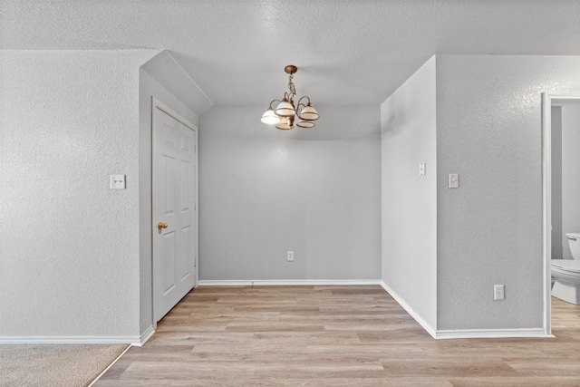 204 Meadowview Ln, Gatesville, TX 76528 - unfurnished room featuring a chandelier, light wood finished floors, a textured wall, and a textured ceiling