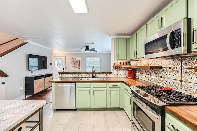 17729 Golden Valley Dr, Manor, TX 78653 - kitchen with green cabinetry, stainless steel appliances, wooden counters, and decorative backsplash