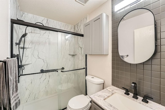 17729 Golden Valley Dr, Manor, TX 78653 - bathroom featuring a marble finish shower, vanity, a textured ceiling, and tile walls