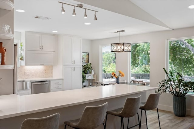 7619 Scenic Brook Dr, Austin, TX 78736 - kitchen featuring a breakfast bar area, dishwasher, light countertops, white cabinetry, and plenty of natural light