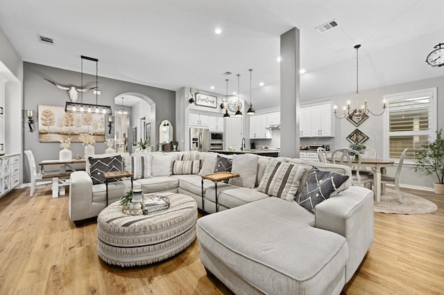 169 Fort Cobb Way, Georgetown, TX 78628 - living room with a chandelier, arched walkways, and light wood-type flooring
