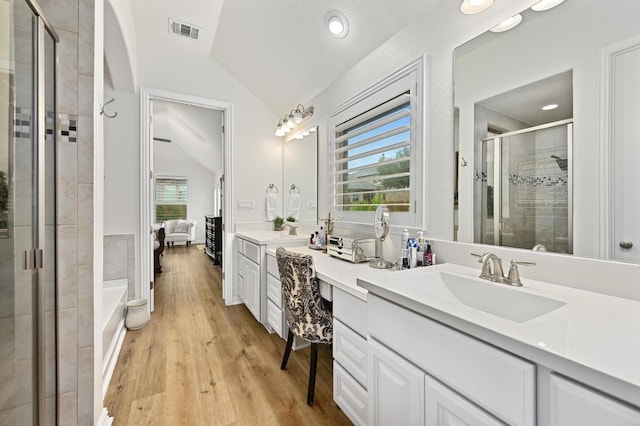 169 Fort Cobb Way, Georgetown, TX 78628 - full bathroom with lofted ceiling, a shower stall, double vanity, wood finished floors, and a garden tub