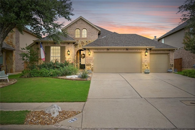 169 Fort Cobb Way, Georgetown, TX 78628 - french country home with a garage, concrete driveway, brick siding, a front lawn, and roof with shingles