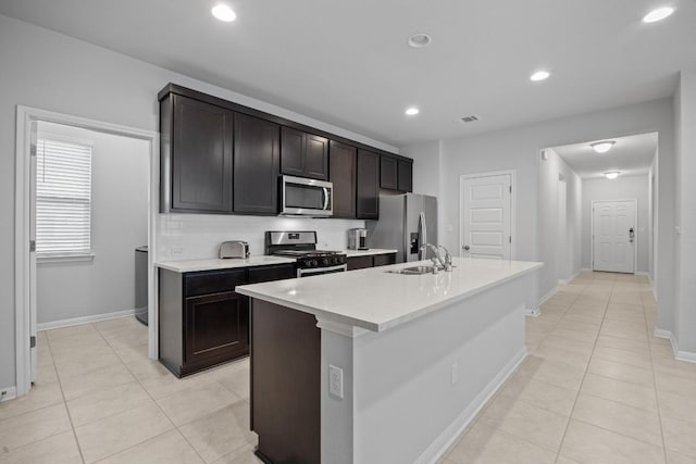 2424 Pecan Island Dr, Leander, TX 78641 - kitchen featuring appliances with stainless steel finishes, light tile patterned floors, light countertops, an island with sink, and recessed lighting