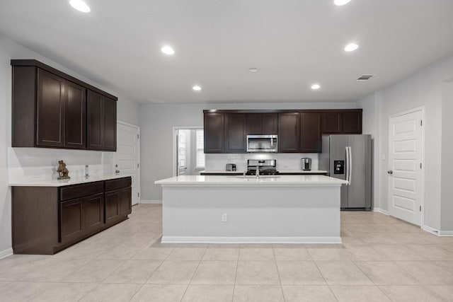 2424 Pecan Island Dr, Leander, TX 78641 - kitchen featuring stainless steel appliances, light countertops, dark brown cabinetry, recessed lighting, and a center island with sink