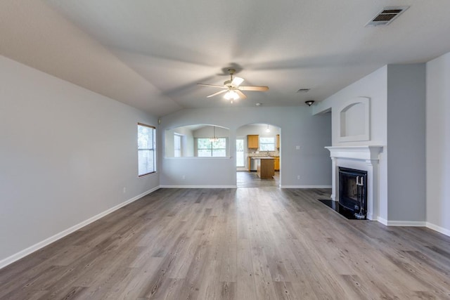 15737 Cadoz Dr, Austin, TX 78728 - unfurnished living room with ceiling fan, arched walkways, wood finished floors, a fireplace, and lofted ceiling