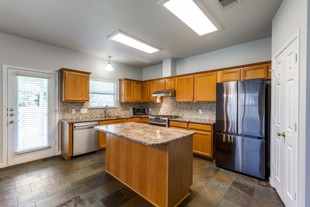 15737 Cadoz Dr, Austin, TX 78728 - kitchen featuring appliances with stainless steel finishes, tasteful backsplash, brown cabinets, and a kitchen island