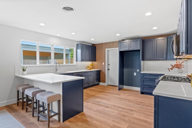 1909 Belford Dr, Austin, TX 78757 - kitchen with a peninsula, a breakfast bar area, stainless steel microwave, light wood-type flooring, and recessed lighting