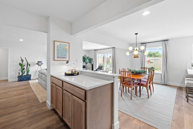 1909 Belford Dr, Austin, TX 78757 - kitchen with light countertops, light wood finished floors, a chandelier, decorative light fixtures, and open floor plan