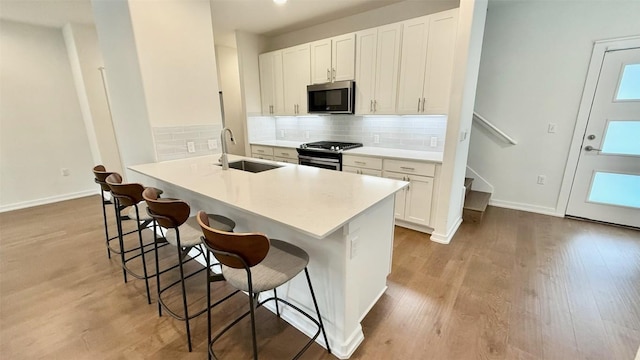 6800 Menchaca Rd Unit 31, Austin, TX 78745 - kitchen featuring stainless steel appliances, a kitchen breakfast bar, light wood-style floors, tasteful backsplash, and white cabinets