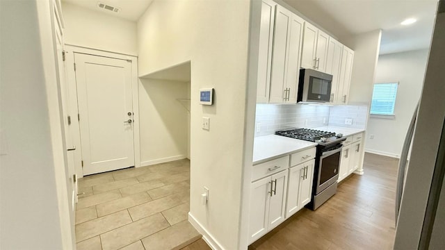 6800 Menchaca Rd Unit 31, Austin, TX 78745 - kitchen with stainless steel appliances, backsplash, light countertops, and white cabinetry