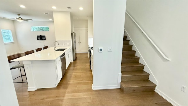 6800 Menchaca Rd Unit 31, Austin, TX 78745 - kitchen with a breakfast bar, appliances with stainless steel finishes, light wood-style flooring, white cabinets, and a ceiling fan