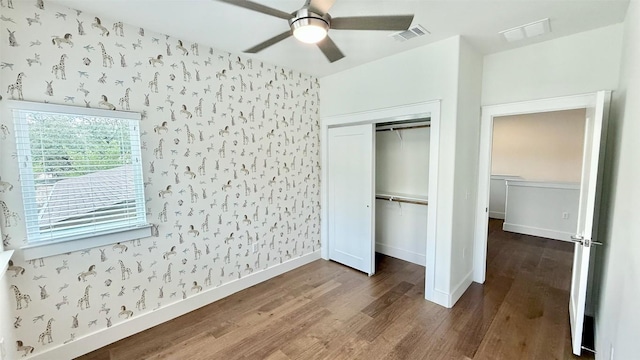 6800 Menchaca Rd Unit 31, Austin, TX 78745 - unfurnished bedroom featuring wood finished floors, wallpapered walls, a closet, and a ceiling fan