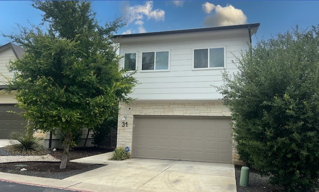 6800 Menchaca Rd Unit 31, Austin, TX 78745 - view of front of home with driveway, an attached garage, and stone siding