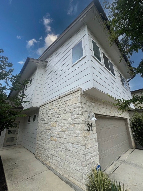 6800 Menchaca Rd Unit 31, Austin, TX 78745 - view of side of home featuring a garage and stone siding