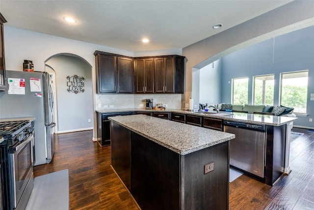 544 Blossom Valley Strm, Buda, TX 78610 - kitchen featuring appliances with stainless steel finishes, arched walkways, a kitchen island, a peninsula, and recessed lighting