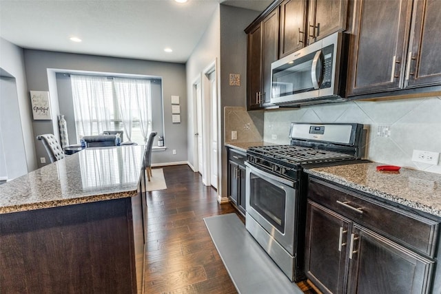 544 Blossom Valley Strm, Buda, TX 78610 - kitchen with appliances with stainless steel finishes, backsplash, light stone counters, dark wood finished floors, and recessed lighting
