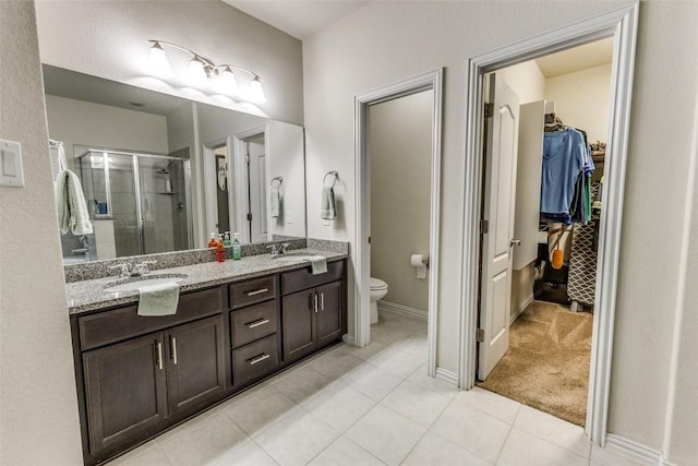 544 Blossom Valley Strm, Buda, TX 78610 - bathroom with a walk in closet, a shower stall, double vanity, and tile patterned floors