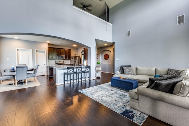 544 Blossom Valley Strm, Buda, TX 78610 - living room featuring arched walkways, dark wood-type flooring, a high ceiling, and a ceiling fan