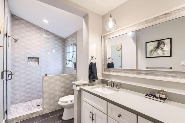7702 Kincheon Ct, Austin, TX 78749 - bathroom with tiled shower, tile patterned flooring, vanity, lofted ceiling, and tile walls