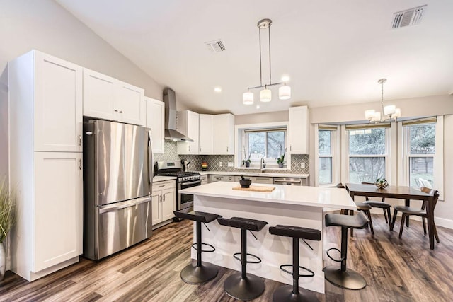 7702 Kincheon Ct, Austin, TX 78749 - kitchen featuring stainless steel appliances, wall chimney exhaust hood, tasteful backsplash, lofted ceiling, and dark wood-style flooring