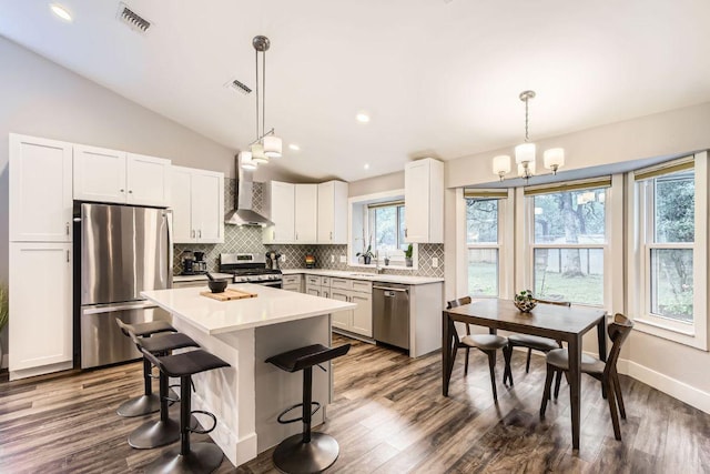7702 Kincheon Ct, Austin, TX 78749 - kitchen featuring stainless steel appliances, wall chimney range hood, decorative backsplash, a breakfast bar area, and light countertops