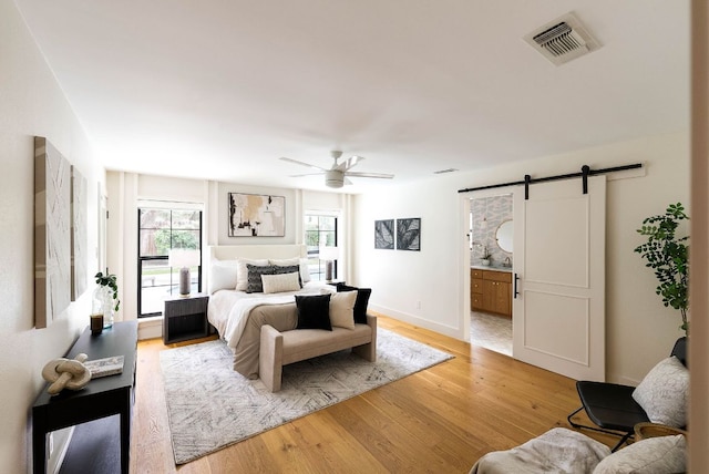 10501 Ronwood Dr, Austin, TX 78750 - bedroom featuring a barn door, light wood finished floors, a ceiling fan, and ensuite bathroom