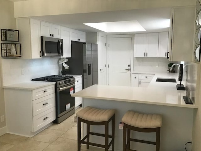 11303 Toledo Dr, Austin, TX 78759 - kitchen with appliances with stainless steel finishes, a peninsula, tasteful backsplash, light countertops, and light tile patterned floors