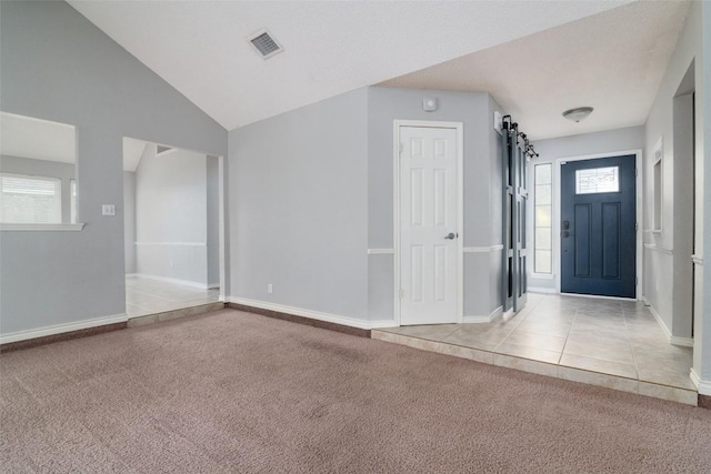 2306 Susan Ln, Leander, TX 78641 - entrance foyer with a barn door, carpet, vaulted ceiling, and tile patterned floors